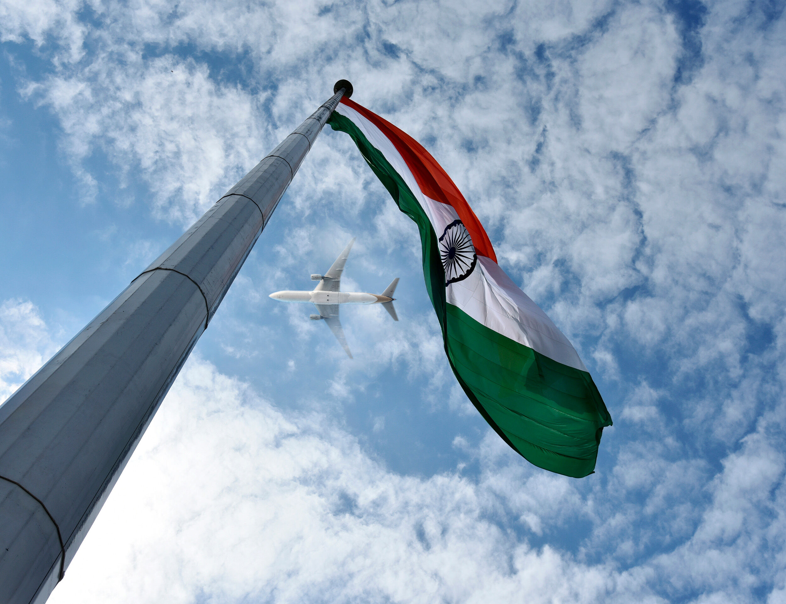 A beautifull picture of indian national falg fluttering in air and a airoplane flying upper him